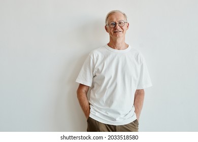 Minimal Waist Up Portrait Of Smiling Senior Man Wearing Glasses While Standing Against White Background, Copy Space