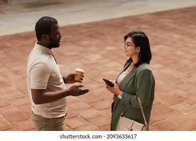 Minimal waist up portrait of two business people chatting in urban city street
