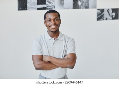 Minimal Waist Up Portrait Of Young Black Artist Smiling At Camera While Standing With Arms Crossed In Gallery Hall, Copy Space