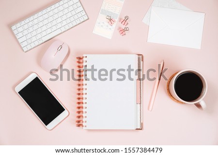 Minimal women office desktop with keyboard, laptop mouse, phone, pen, coffee mug and notebook on pink background. Flat lay, top view, space for text.