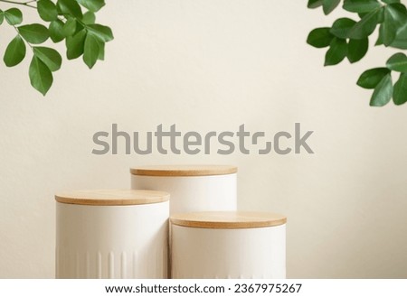 Minimal wood white podium with blurred green leaf plant on beige background.Beauty cosmetic natural mild product modern display,nature eco friendly concept.