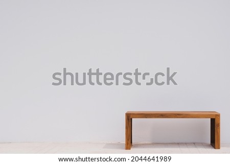 Minimal wooden bench with a white wall background and copy space