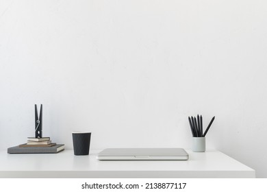 Minimal Workspace, Desk With Laptop Closed Office Supplies, Coffee Paper Cup And Empty Wall Background.