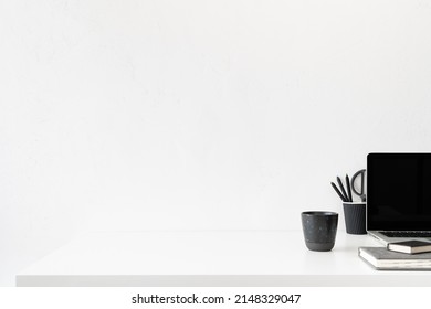 Minimal Workspace, Desk With Laptop, Office Supplies, Coffee Ceramic Cup And Empty Wall Background.