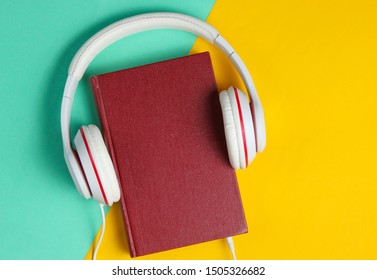 Minimalism Online Listen To Books Concept. Audiobook Book With Headphones On Colored Background. Top View