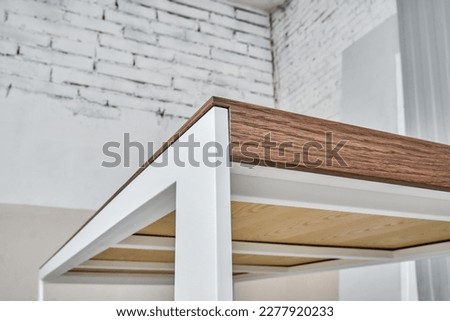 Minimalism style dining table with thin wooden table top of oak veneer on white metal legs in workshop closeup low angle view