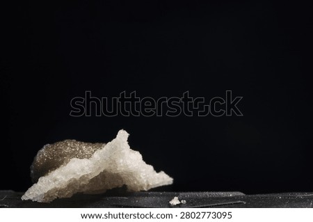 Minimalist abstract background featuring a textured white crystal stone against pitch black backdrop