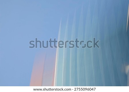 A minimalist, abstract composition featuring the vertical lines of a modern glass building fading into a clear blue sky. The image utilizes a soft focus and intentional motion or light refraction to create a rhythmic, ethereal pattern. Hues of pale blue, teal, and a warm sunset glow on the left edge evoke a sense of serenity, futuristic design, and architectural elegance.