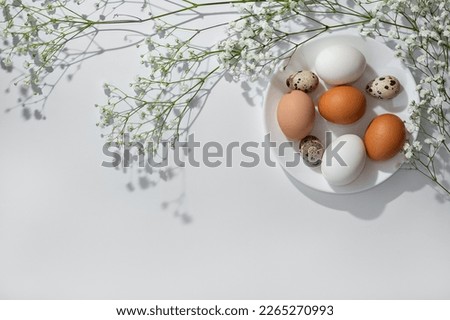 Minimalist aesthetic Easter design, flowers and a plate with natural color eggs on neutral background, elegant Easter card template, copy space