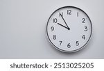 Minimalist Analog Wall Clock with White Face and Simple Black Hands Showing 21.55, 09.55. Ideal for Time Management and Modern Decor Concepts