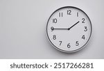 Minimalist Analog Wall Clock with White Face and Simple Black Hands Showing 13.45, 01.45. Ideal for Time Management and Modern Decor Concepts