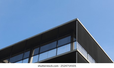 A minimalist architectural element showcasing a modern building's exterior. The clean lines and dark facade contrast sharply against the bright blue sky.