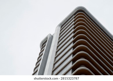 Minimalist architectural facade featuring repeating curved balconies. A study in rhythm, geometry, and modern design with a palette of slate grey and warm terracotta tones against a neutral sky.