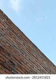 Minimalist architectural shot featuring the sharp diagonal edge of a brick building frame against a clear blue sky
