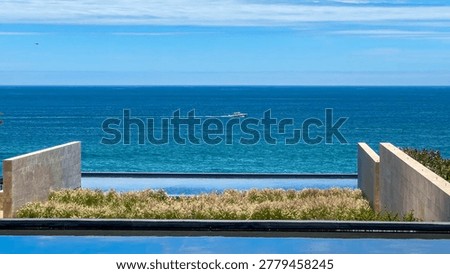 Minimalist architectural view of an infinity pool looking out to the vast ocean with a lone boat on the horizon