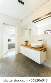 Minimalist Bathroom Interior With Mirror, Decorative Lighting, Wooden Worktop And Basin