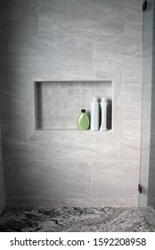 Minimalist Bathroom Shower With Gray Tile And Niche Shelf With Shampoo Bottles And Granite Bench