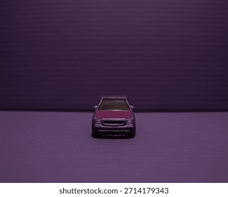 A minimalist, centered, eye-level front view of a metallic purple die-cast model car against a monochromatic purple background with horizontal lines, emphasizing symmetry and clean design.