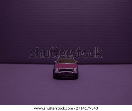 A minimalist, centered, eye-level front view of a metallic purple die-cast model car against a monochromatic purple background with horizontal lines, emphasizing symmetry and clean design.