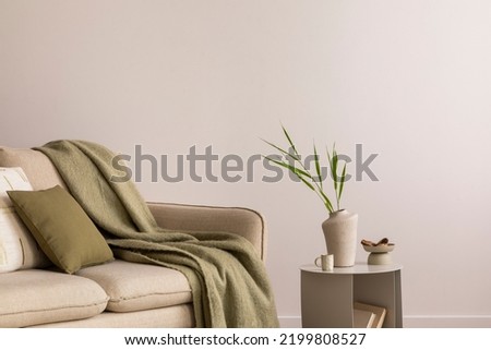 Minimalist composition of elegant and outstanding space with beige sofa, coffee table, vase, green plaid and pillow. Beige wall. Home decor. Template. 