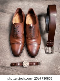 
A minimalist composition featuring three essential men's fashion accessories: shoes, belt, and watch. Neutral colors and simple lines create a clean, elegant look, perfect for everyday outfits