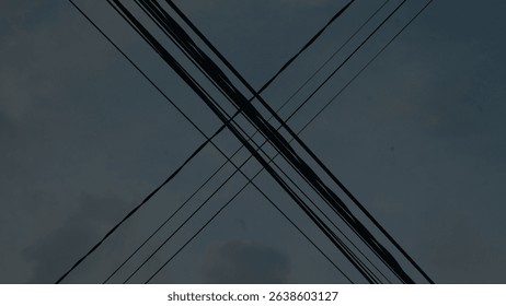 Minimalist composition of intersecting utility cables forming an X shape against clear sky in daylight and dusk tones. Ideal for abstract, infrastructure, or urban concept visuals.