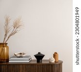 Minimalist composition of living room interior with copy space, wooden commode, vase with dried flowers, candle, black books and personal accessories. Home decor. Template. 