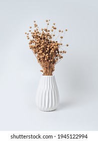 Minimalist composition in a stylish white vase with dried flowers. A bouquet of dry flax on a light background. Decor for home interior decoration.