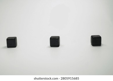 Minimalist composition of three small black cubes isolated on white background.