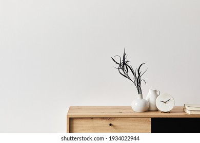 Minimalist concept of living room interior at elegant apartment with wooden commode, leaf in ceramic vase, clock and elegant personal accessories in modern home decor. Copy space. Template. . - Powered by Shutterstock