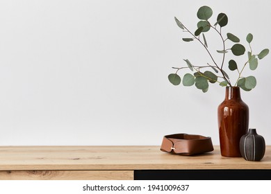 Minimalist concept of living room interior at elegant apartment with wooden commode, leaf in ceramic vase and elegant personal accessories in modern home decor. Copy space. Template. . - Shutterstock ID 1941009637