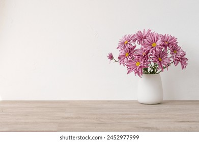 Minimalist floral product background with empty copy space, wooden beige neutral table, white concrete wall surface, vase with pink daisy flowers bouquet, aesthetic home interior decor mockup. - Powered by Shutterstock