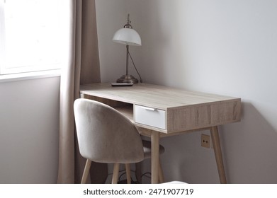 minimalist home office setup with a wooden desk, chair, and desk lamp by window.  - Powered by Shutterstock