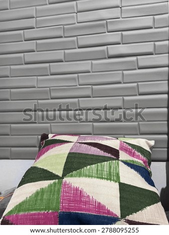 Minimalist interior corner featuring a geometric patterned cushion against a textured white brick wall background
