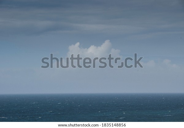 Minimalist landscape of sky\
over ocean, with horizon line dividing the frame. Blue tones,\
vertical symmetry