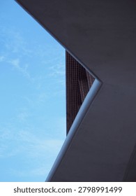A minimalist low-angle perspective features a geometric white frame looking up at a contemporary red brick building facade against a clear blue sky, ideal for urban architectural design concepts.