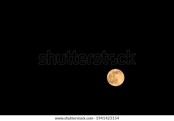 Minimalist nature background with lonely moon in the\
night sky. Minimal dark landscape with bright orange moon in pitch\
darkness. 
