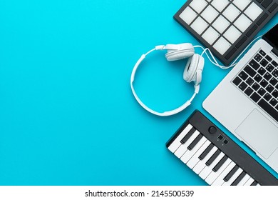 Minimalist photo of bedroom producer setup over turquoise blue background. Top view of home studio music production equipment with copy space. Modern beatmaker essential studio equipment.