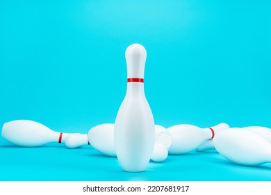 Minimalist Photo Of Bowling Pin Over Turquoise Blue Background. One Standing White Bowling Pin In Front Of Knocked Down Pins. Bad Times Financial Business Survival Concept.