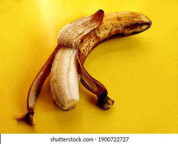 A Minimalist Photo Of One Ripe Bannana Peeled To Half, With A Beautiful Golden Bannana Peel. Dark Yellow Background With Discreet Shadow Of Bannana. 