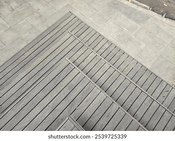 A minimalist photograph showcasing the geometric pattern of wooden steps meeting concrete pavement. - Powered by Shutterstock