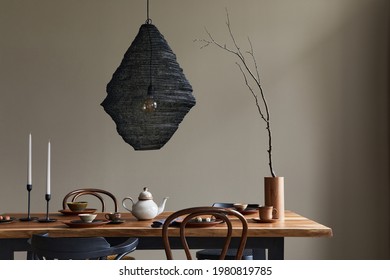 Minimalist rustic concept of dining room interior with wooden family table, design retro chairs, cup of coffee, decoration, pedant lamp and personal accessories in stylish home decor. Template.