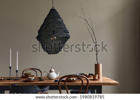Minimalist rustic concept of dining room interior with wooden family table, design retro chairs, cup of coffee, decoration, pedant lamp and personal accessories in stylish home decor. Template.