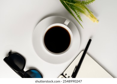 A minimalist setup featuring a cup of black coffee, sunglasses, notebook, and pen on a white background. Ideal for concepts of relaxation, planning, and creativity. - Powered by Shutterstock