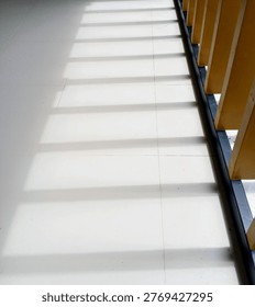Minimalist shadow pattern from window blinds on white floor tiles. Abstract geometric light and shadow in interior detail.