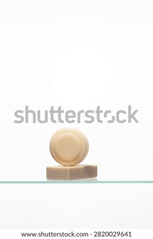 A minimalist stack of two artisanal soap bars-one round, one rectangular-showcasing natural, uncolored tones. Represents a simple, gentle skincare and personal hygiene routine.