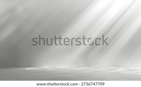 A minimalist studio setting with soft, angled light rays creating dramatic shadows on a lightly textured floor and wall.