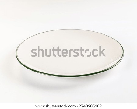 Minimalist studio shot of a single, empty white plate with a dark green rim. High-key lighting on a clean white background. Classic, simple design for food, dining, or conceptual use.