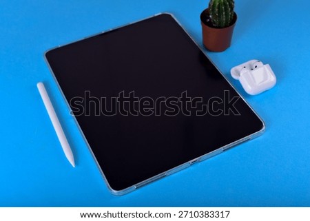 Minimalist tech setup with tablet, stylus, and earbuds