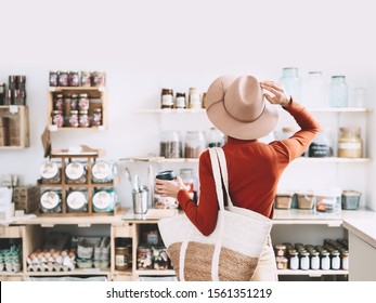 Minimalist vegan style girl with wicker bag and reusable glass coffee cup on background of interior of zero waste shop. Woman doing shopping without plastic packaging in plastic free grocery store. - Powered by Shutterstock